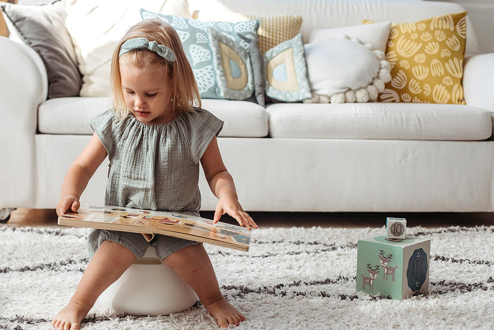 Child playing with a book in a living room